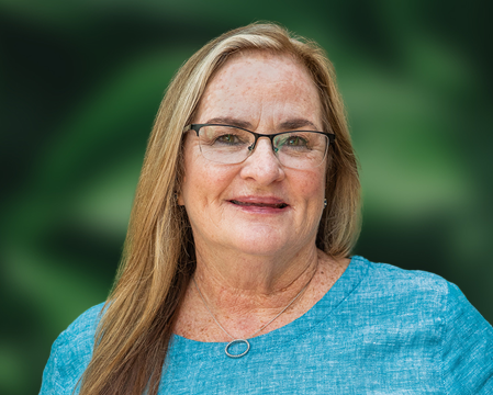 Alliant National's Mary Berner stands in front of a background.